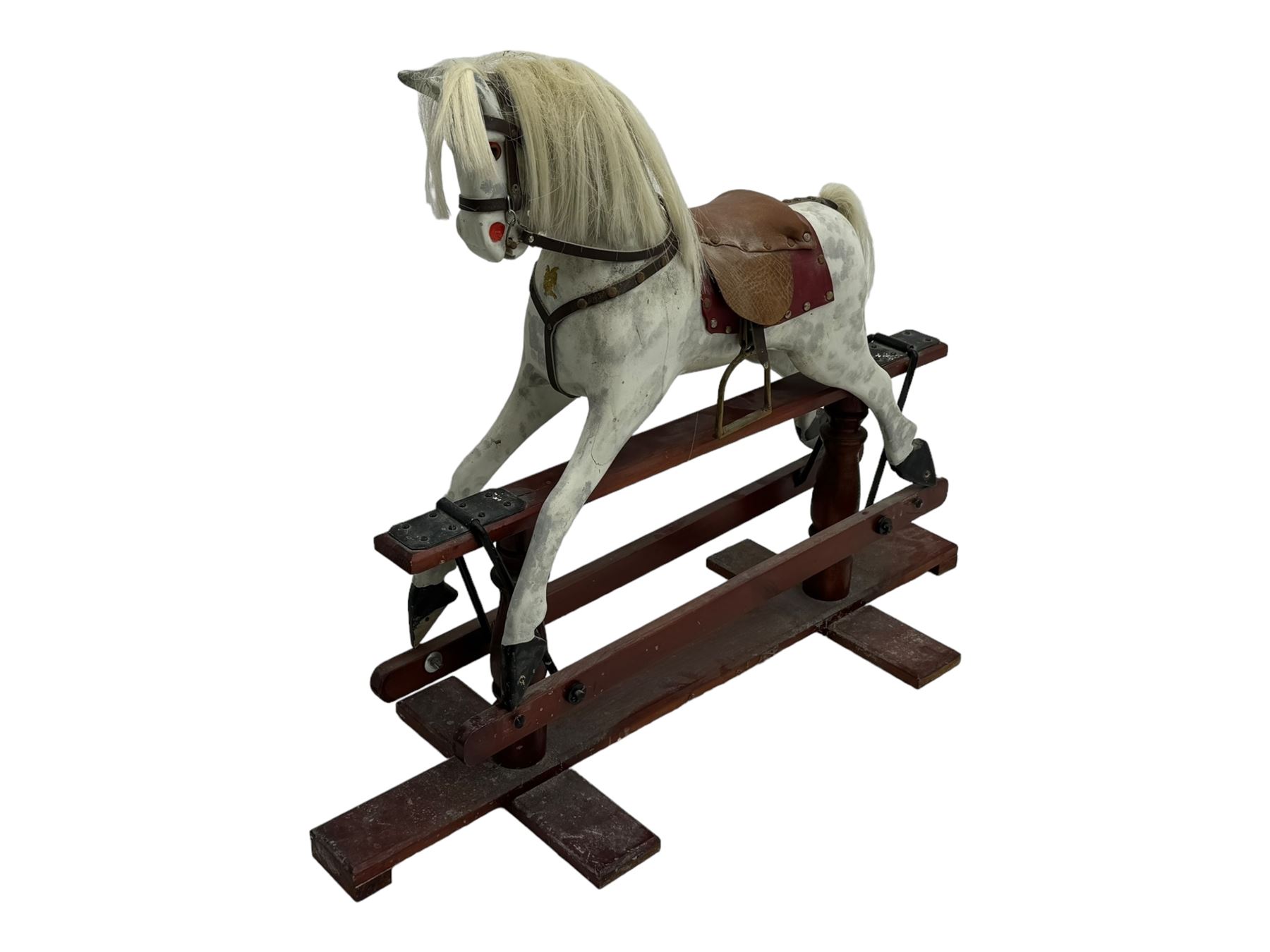 Mid 20th century rocking horse, dappled grey painted horse with applied mane and tail, red leather saddle and bridle accented with brass studs, supported by a stained wooden frame with turned supports and iron brackets, mounted on rockers