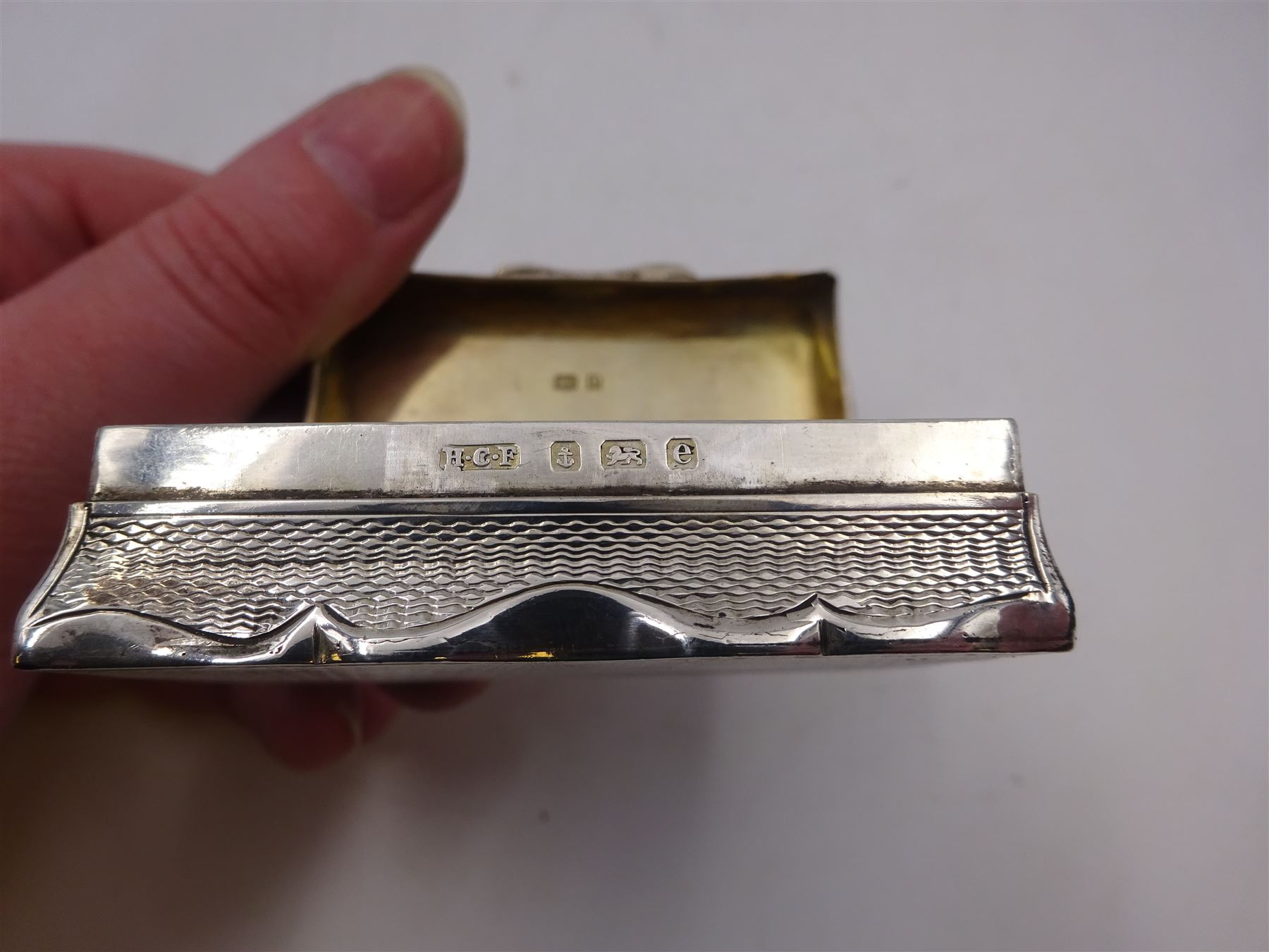 Edwardian silver snuff box, of rectangular form, with shaped edges, engine turned decoration throughout and engraved cartouche to hinged cover, opening to reveal a gilt interior, hallmarked Henry Charles Freeman, Birmingham 1904, W6cm