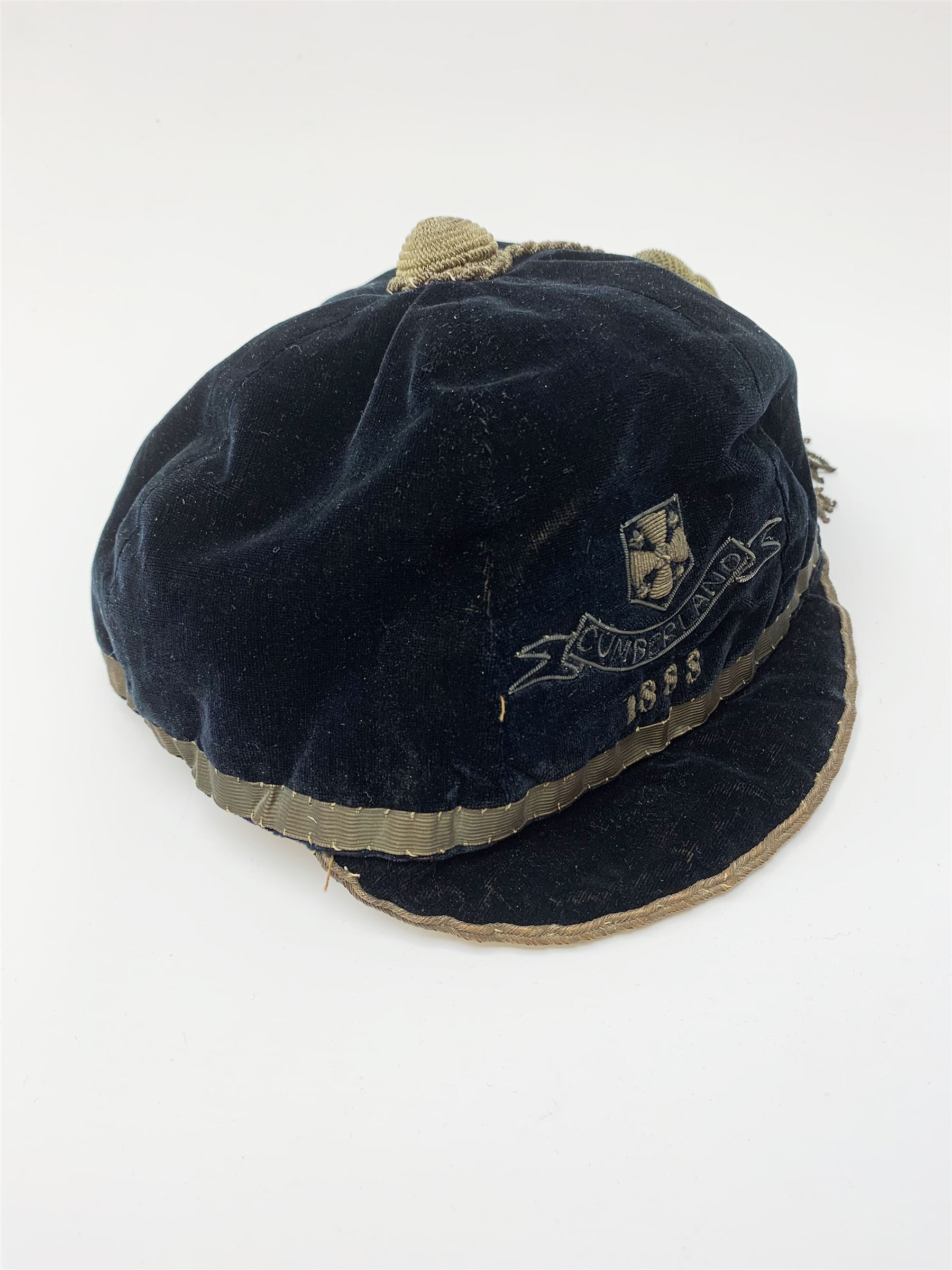 A Victorian rugby cap for Cumberland, the black velvet cap with gold coloured thread and tassel, dated 1888. 