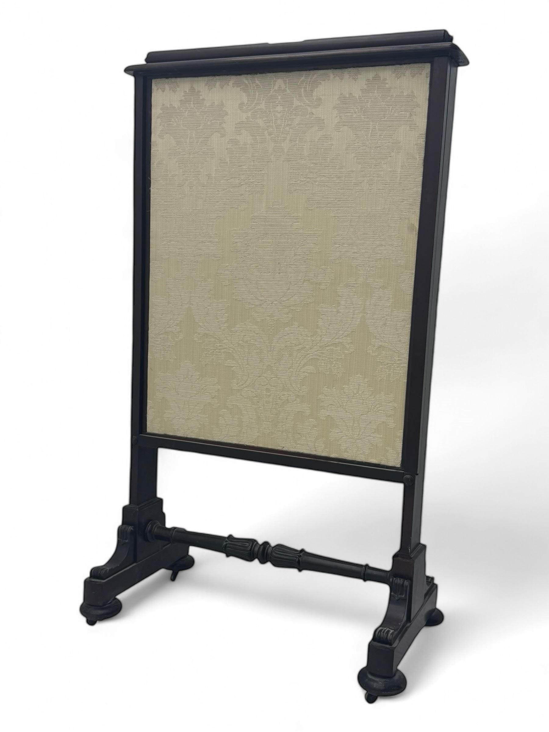 Early 19th century mahogany fire screen, upholstered in cream foliate pattern fabric, pull-up panel and sliding panel, raised on platforms united by turned and lappet carved stretcher, on compressed bun feet with castors 