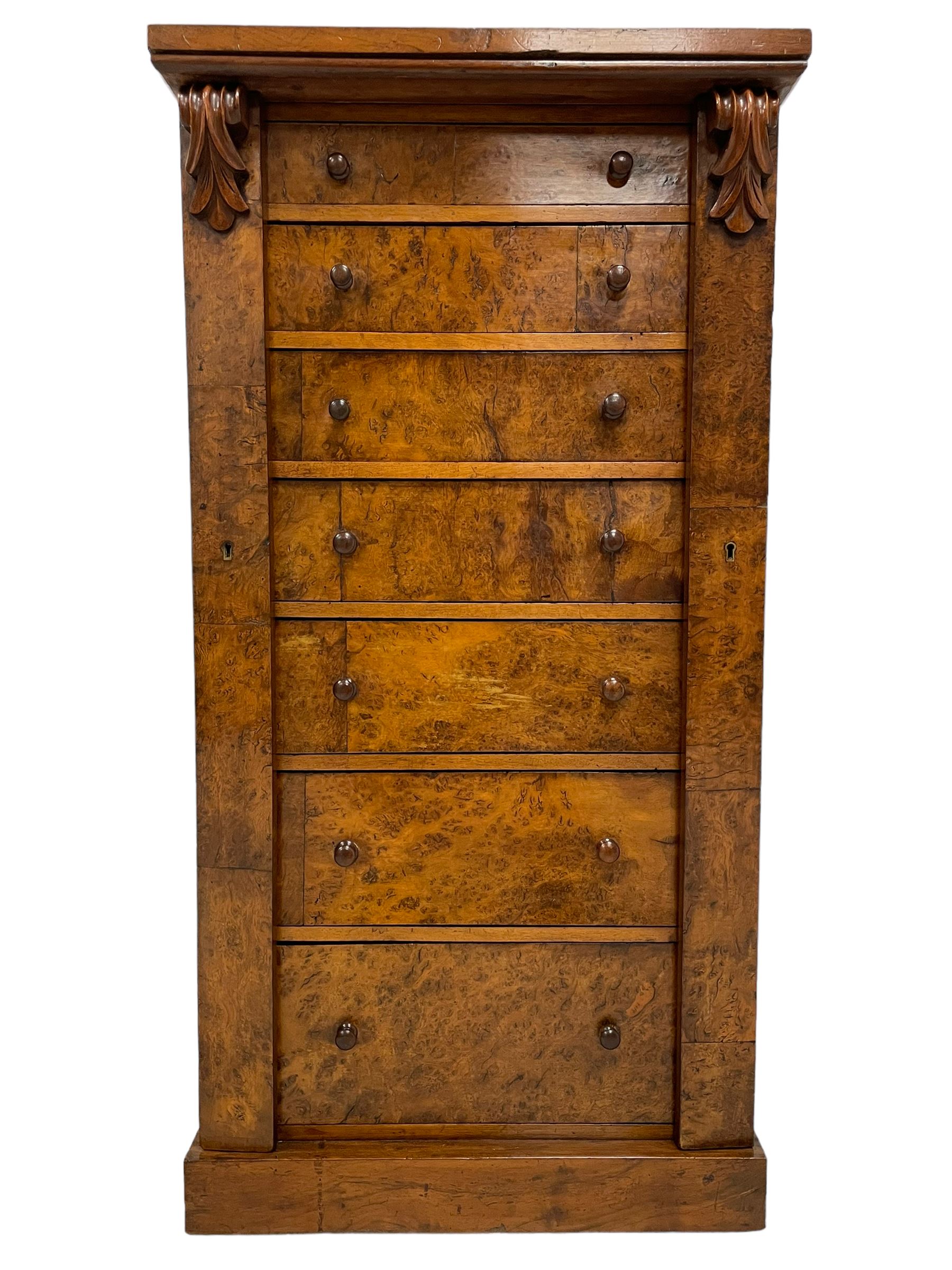 Victorian burr walnut Wellington chest, rectangular top with book-matched veneers, two hinged uprights with scrolled foliage carved brackets enclosing seven graduating drawers, on plinth base 