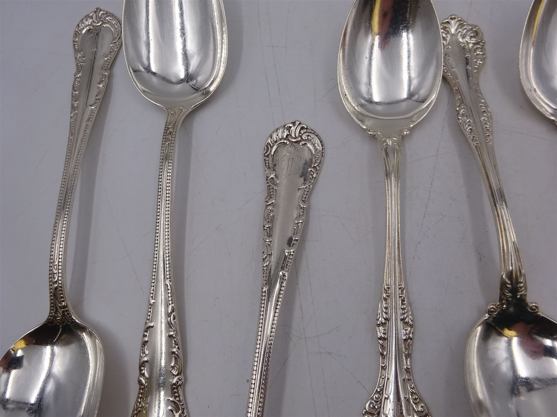 Group of American silver flatware, comprising set of three table spoons, each with beaded stem and engraved with initialsm marked for Mermod & Jaccard Jewelery Co. and a set of six American silver dessert spoons, each engraved with initial in a scrolling border, stamped Sterling