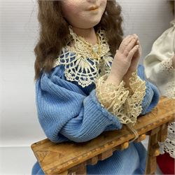 Anna Meszaros Hungary - two hand made needlework figurines, each of a young girl kneeling by an alter rail praying H28cm; together with another similar of a chorister H29cm (3)  Auctioneer's Note: Anna Meszaros came to England from her native Hungary in 1959 to marry an English businessman she met while demonstrating her art at the 1958 Brussels Exhibition. Shortly before she left for England she was awarded the title of Folk Artist Master by the Hungarian Government. Anna was a gifted painter of mainly portraits and sculptress before starting to make her figurines which are completely hand made and unique, each with a character and expression of its own. The hands, feet and face are sculptured by layering the material and pulling the features into place with needle and thread. She died in Hull in 1998.