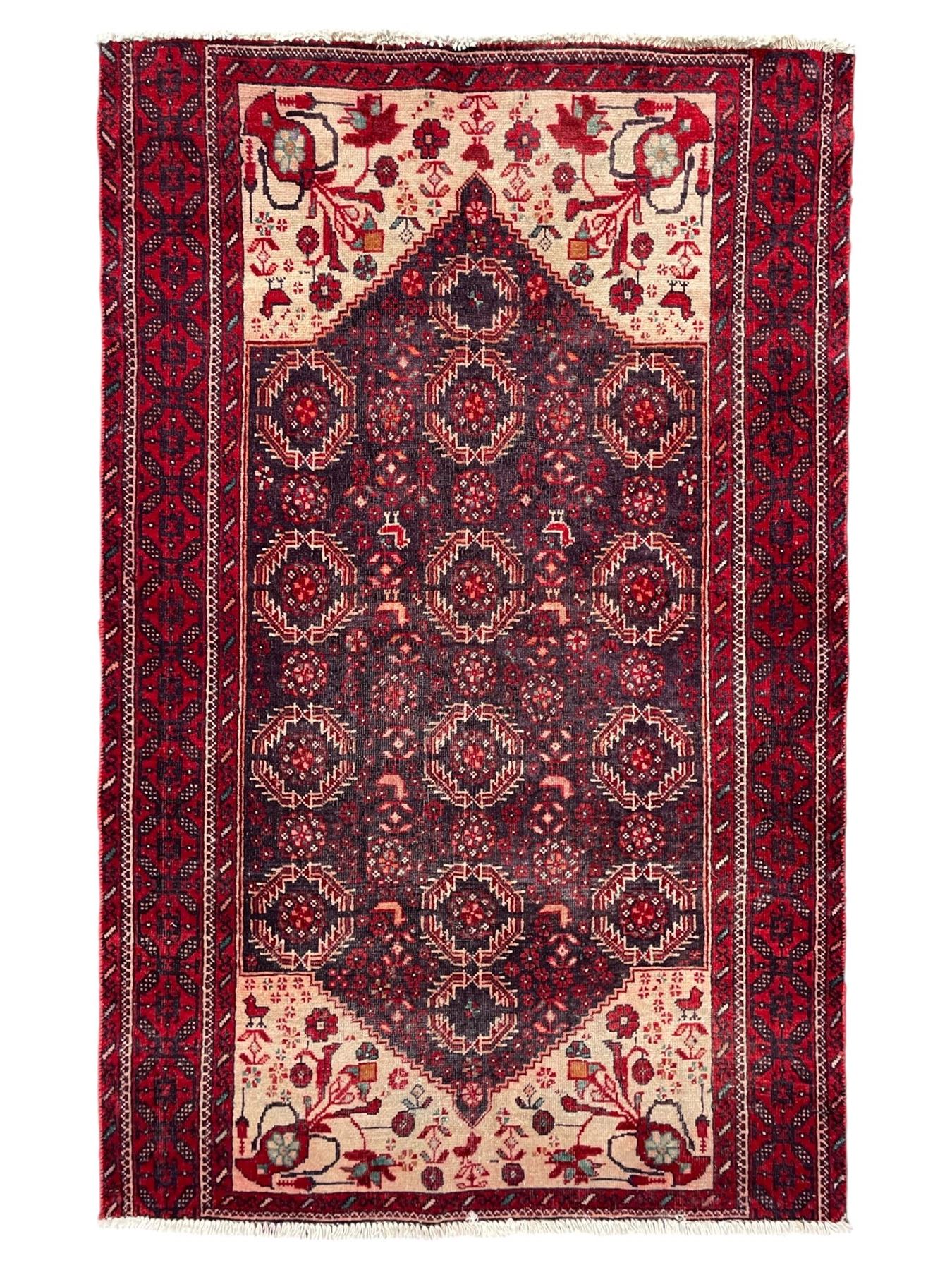 Persian Baluchi dark indigo and crimson ground rug, the field decorated with rows of repeating Pitrak motifs and surrounded by small bird and flower head motifs, floral urn decorated spandrels, repeating Pitrak border within guard stripes