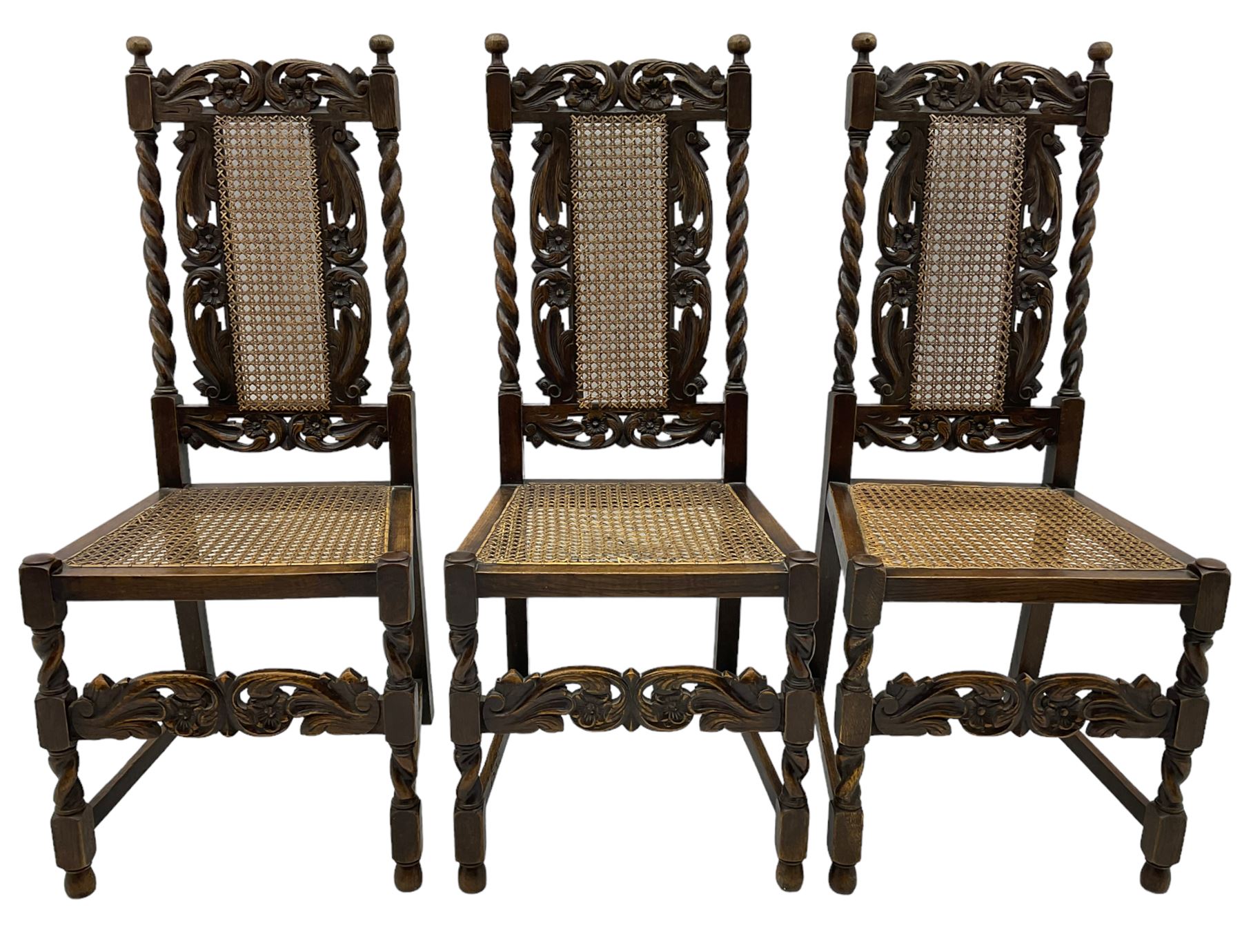 Set of seven (5+2) 19th century Carolean design oak dining chairs, scroll leaf and flower head carved cresting rail over spiral turned uprights and cane work back, the cane work seat on spiral turned supports united by plain stretchers, scrolled leaf carved middle rail 