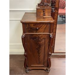 Tall Victorian figured mahogany twin pedestal dressing table, the tall mirror with flower head and scrolled leaf carved pediment, flanked by two turned and carved finials over faceted lancet arched lantern tops, plane mirror plate enclosed by shaped frame, pierced and undulating moulded uprights, on C-scroll and curled leaf carved supports fitted with cast brass hinged candle sconces, each pedestal fitted with two small trinket drawers over larger drawer and panelled cupboard, canted corners with matched upright mounts, the cupboard doors enclosing slides, on scroll carved feet 