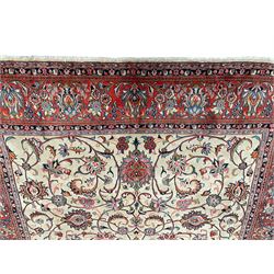 Persian Sarough ivory ground rug, the field decorated with curled leafy branches and palmettes, crimson ground border decorated with further palmettes and floral sprays, within guard stripes 