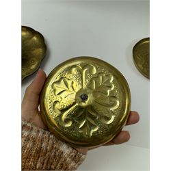 Three Arts & Crafts brass chambersticks/candlesticks, to include a small Keswick School of Industrial Arts example, with repousse leaf decoration, stamped KSIA, a chamberstick with Art Nouveau style decoration to drip pan and blue enamel roundel inset into the loop handle and a larger candlestick, with shaped rim and sconce, repousse decoration and lightly hammered finish, largest D18cm