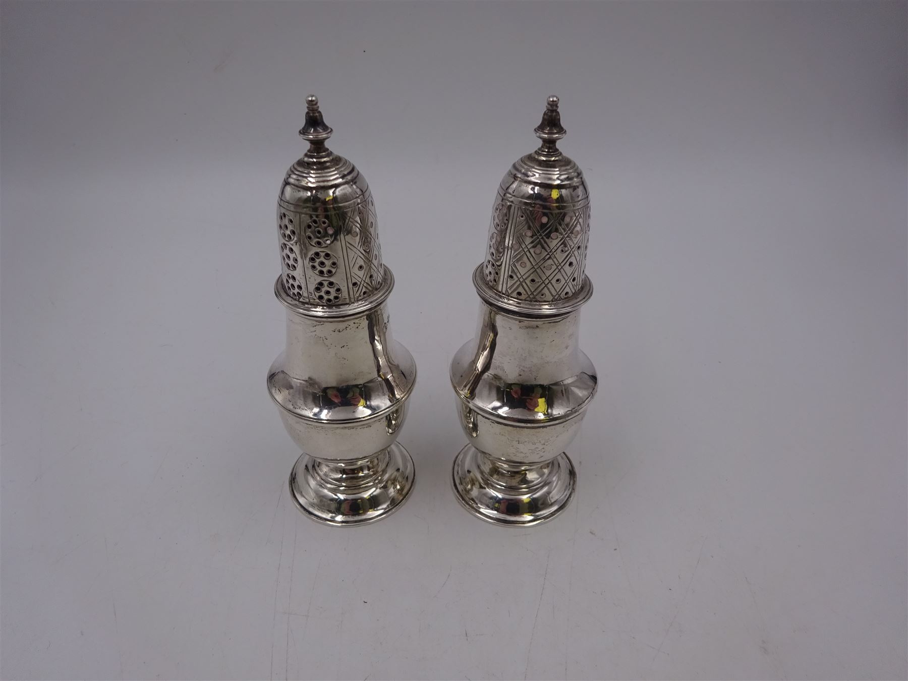 Pair of Victorian silver sugar casters, of typical waisted form, the removable pierced cover with urn finial, upon domed circular foot, hallmarked Sheffield 1880, maker's mark WB, H14.5cm