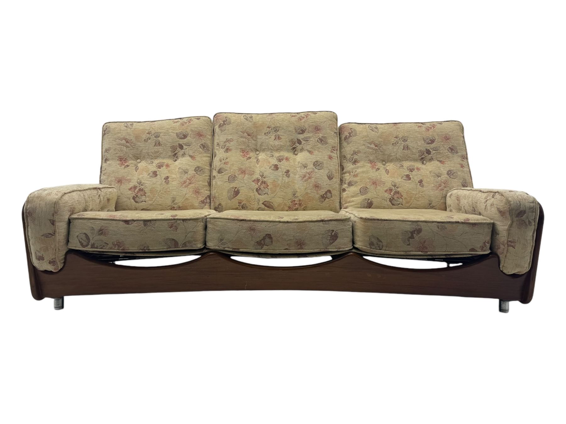 Mid-20th century three-seat sofa with floral patterned upholstery, supported by a sculpted teakwood frame with curved cutout detailing, loose cushioned back and seat, on tubular metal feet