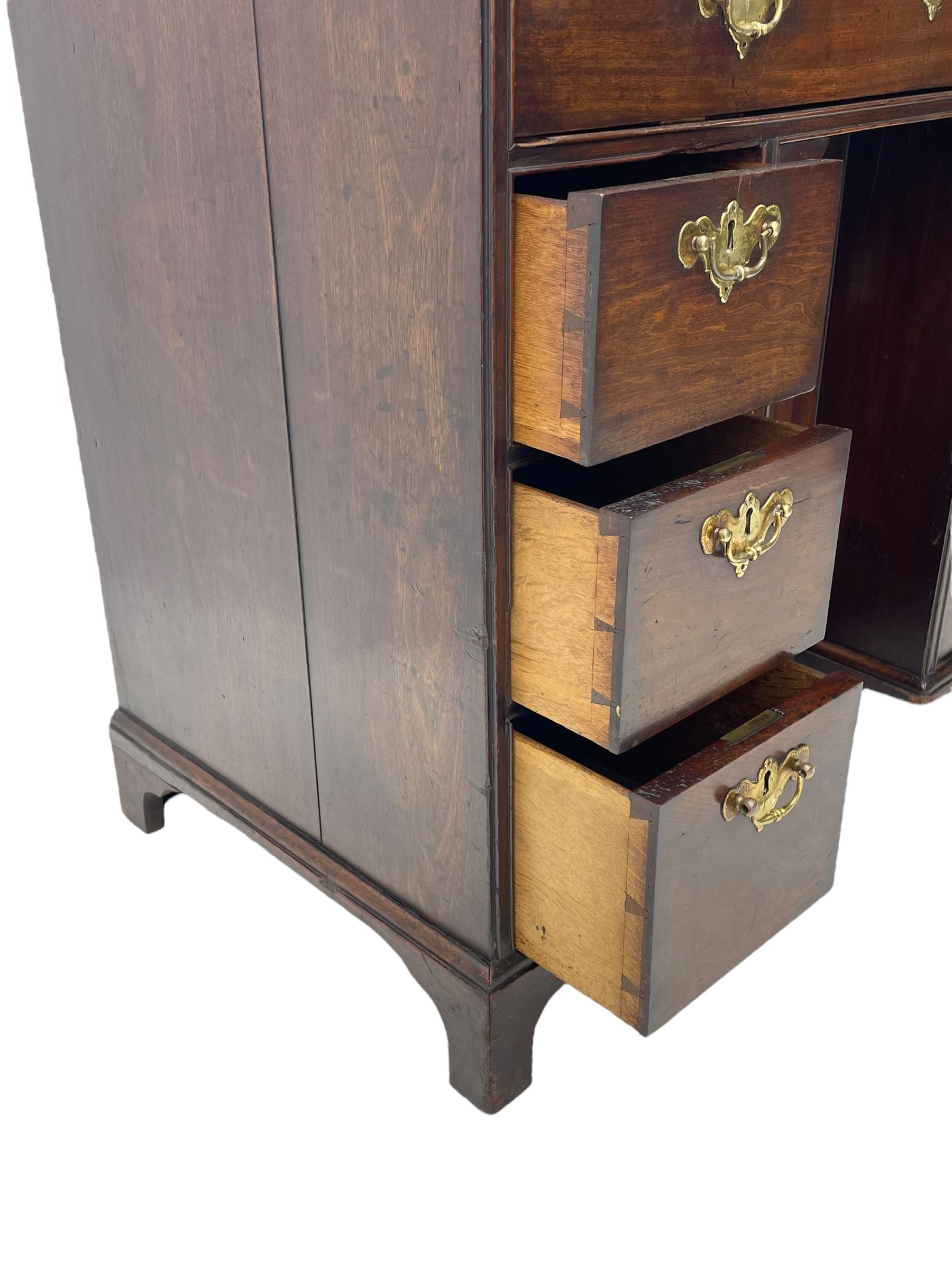 George III mahogany kneehole desk, moulded rectangular top over one long drawer, six short drawers and recessed panelled cupboard, cock-bead moulded frame, fitted with shaped brass handle plates with engraved decoration, on bracket feet 