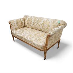 19th century gilt wood and gesso settee, upholstered in repeating floral pattern fabric, rolled arms decorated with trailing bead moulding and acanthus leaf, the seat rail with flower head band, on twist turned and foliate carved feet with brass castors 