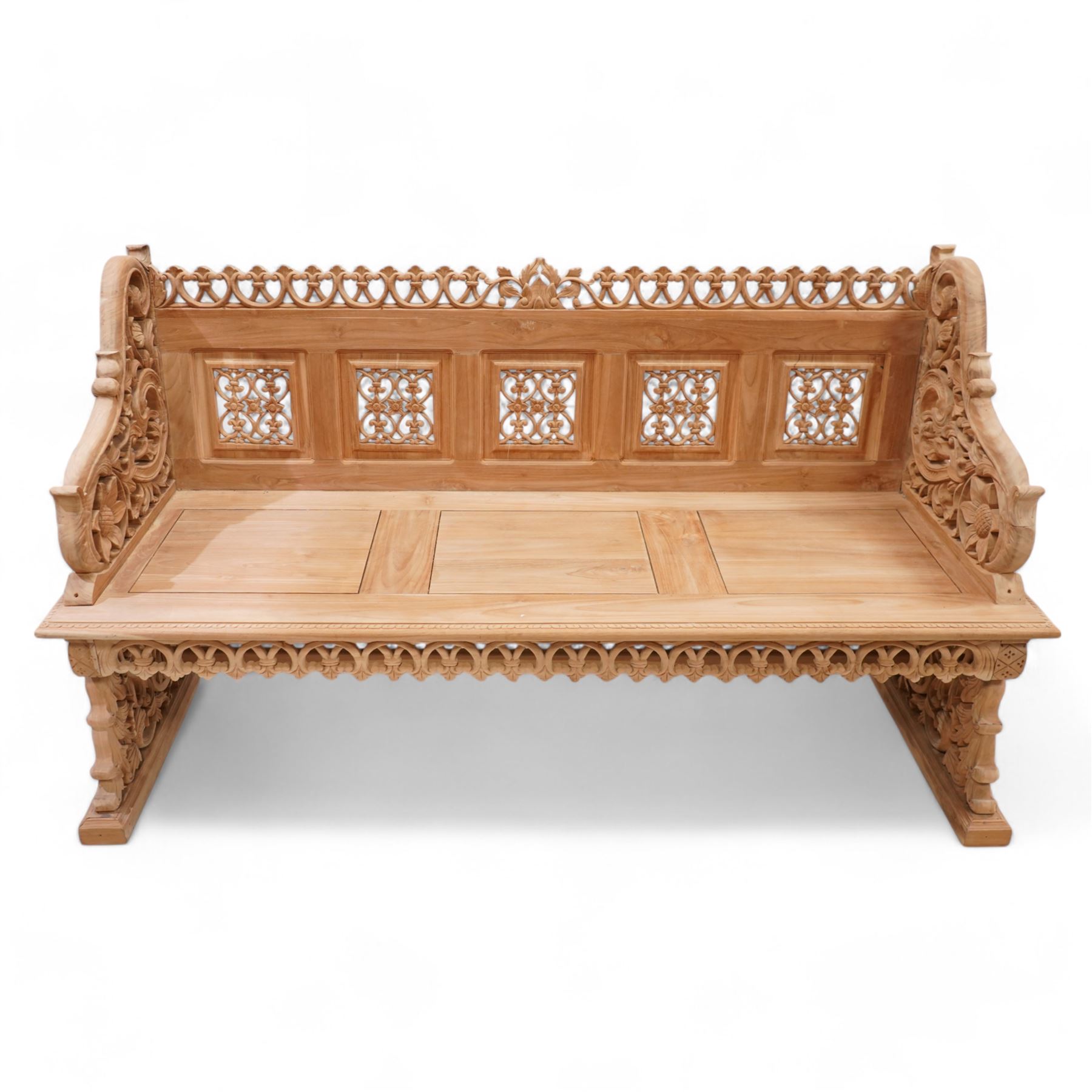 Hand carved teak garden bench, C-scroll and foliate carved cresting rail over four pierced and flower head carved panels, shaped and scrolling end supports carved with flower heads and curling leafy branches, united by pegged stretcher