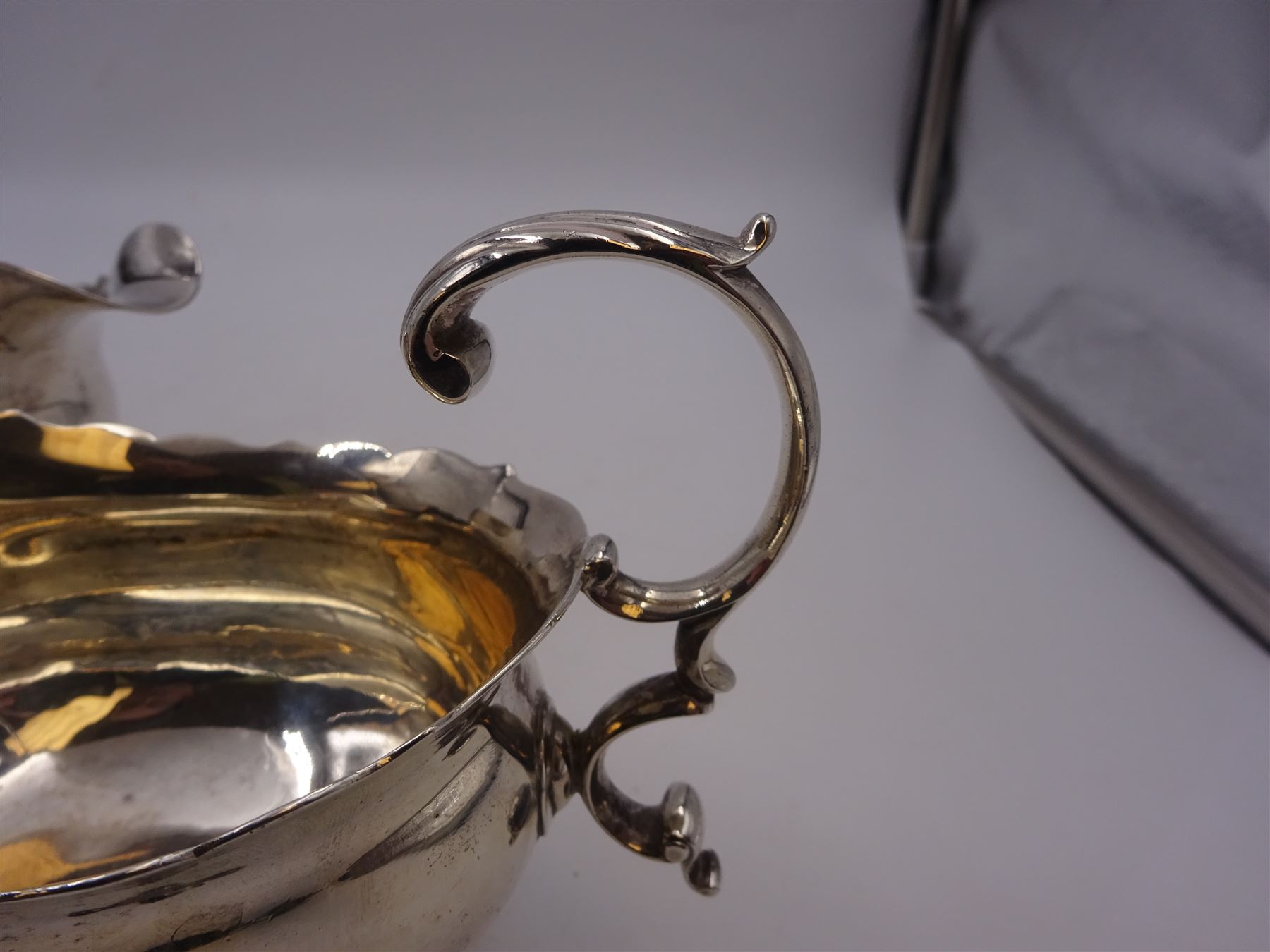 Near pair of George II silver sauce boats, each of oval form with shaped rim and capped flying scroll handle, upon three scroll mounted feet, hallmarked David Hennell, London 1758, H12cm