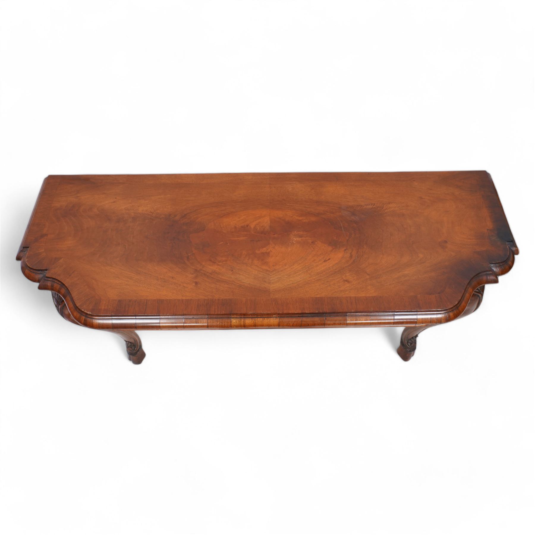 Pair of Georgian walnut console tables, the shaped rectangular cross-banded top with moulded edge over a banded frieze, raised on moulded cabriole supports decorated with scalloped shell and scroll carved knees, terminating to hairy hoof feet