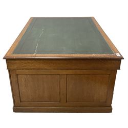 Late 19th century twin pedestal oak partner's desk, rectangular top with inset green leather writing surface, fitted with nine graduating drawers to each side, the rear drawers enclosed by panelled cupboards