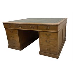 Late 19th century twin pedestal oak partner's desk, rectangular top with inset green leather writing surface, fitted with nine graduating drawers to each side, the rear drawers enclosed by panelled cupboards