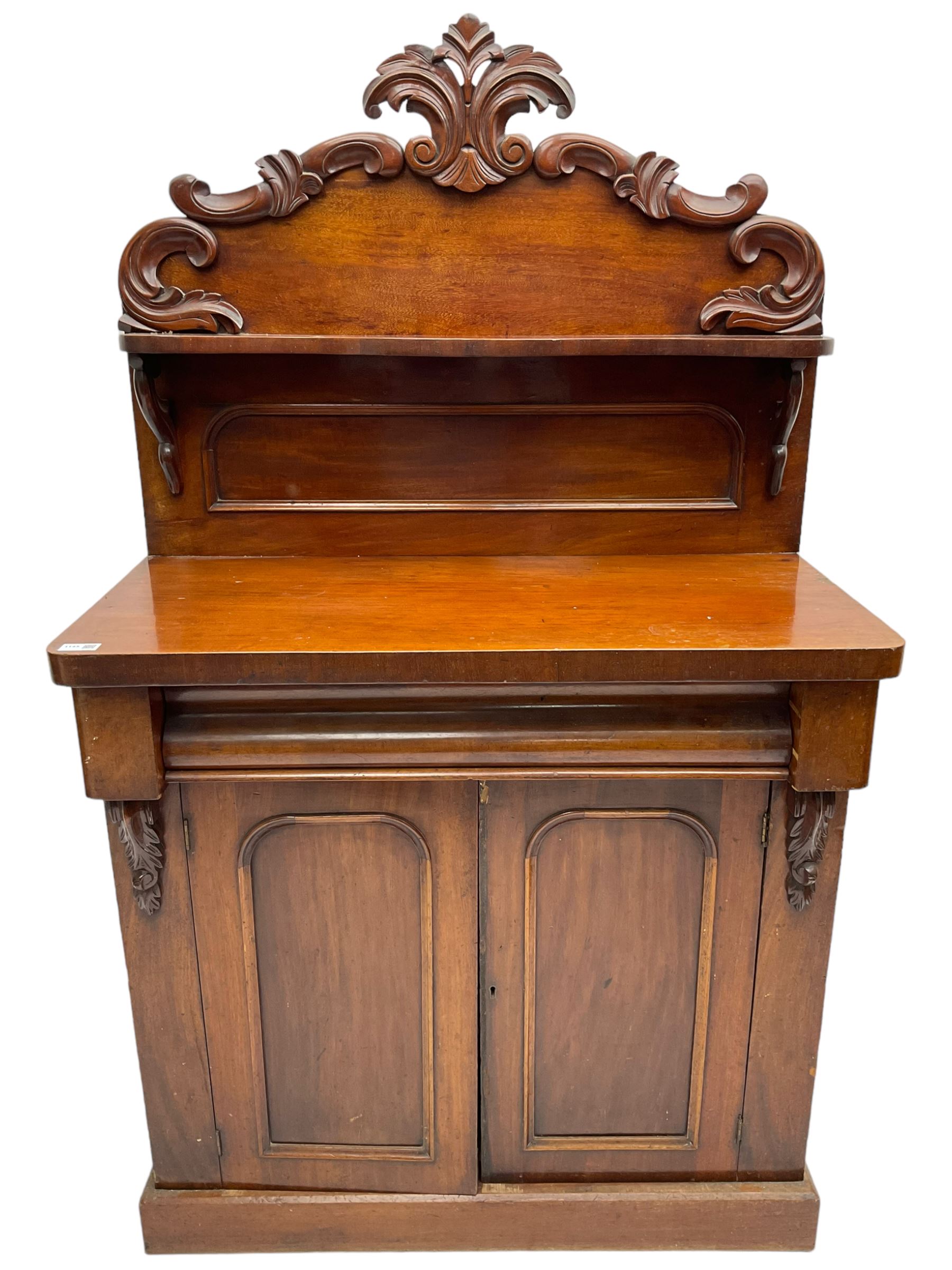 Victorian mahogany chiffonier, raised back with carved C-scroll foliage mounts and shelf, rectangular top with rounded corners over frieze drawer and double panelled cupboard, on skirted base