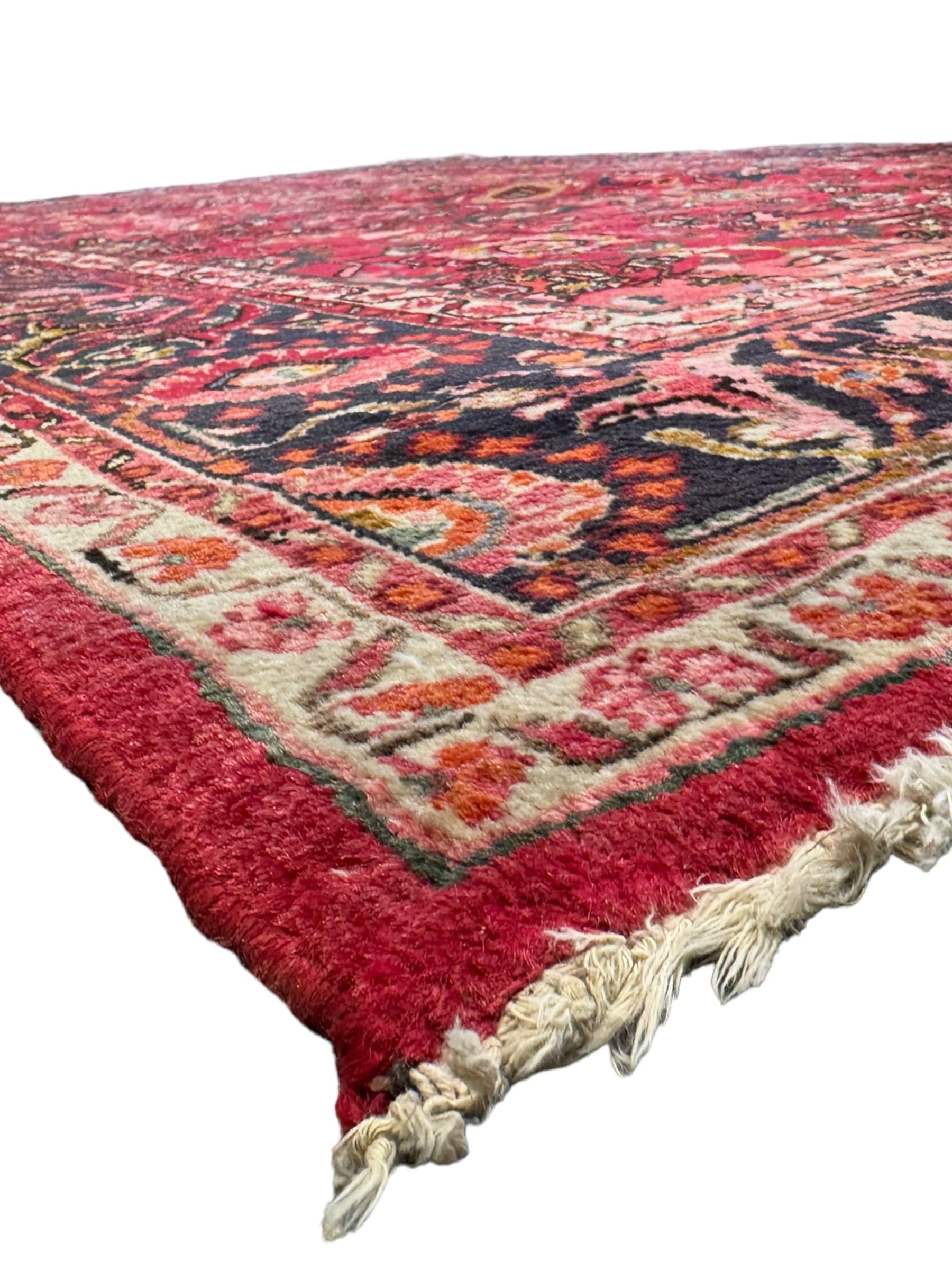 Persian Nanaj crimson ground carpet, the busy field filled with interconnecting stylised plant motifs with scrolling branches, the guarded indigo border decorated with repeating palmettes and foliate patterns