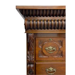 Late Victorian walnut Scotch chest, projecting cornice with turned quarter column mounts over matching half column to frieze, fitted with two upper short drawers with central cupboard, bevelled mirror glazed cupboard door, four graduating drawers below, foliage and flower head carved brackets to the uprights, panelled sides, chamfered plinth on turned feet