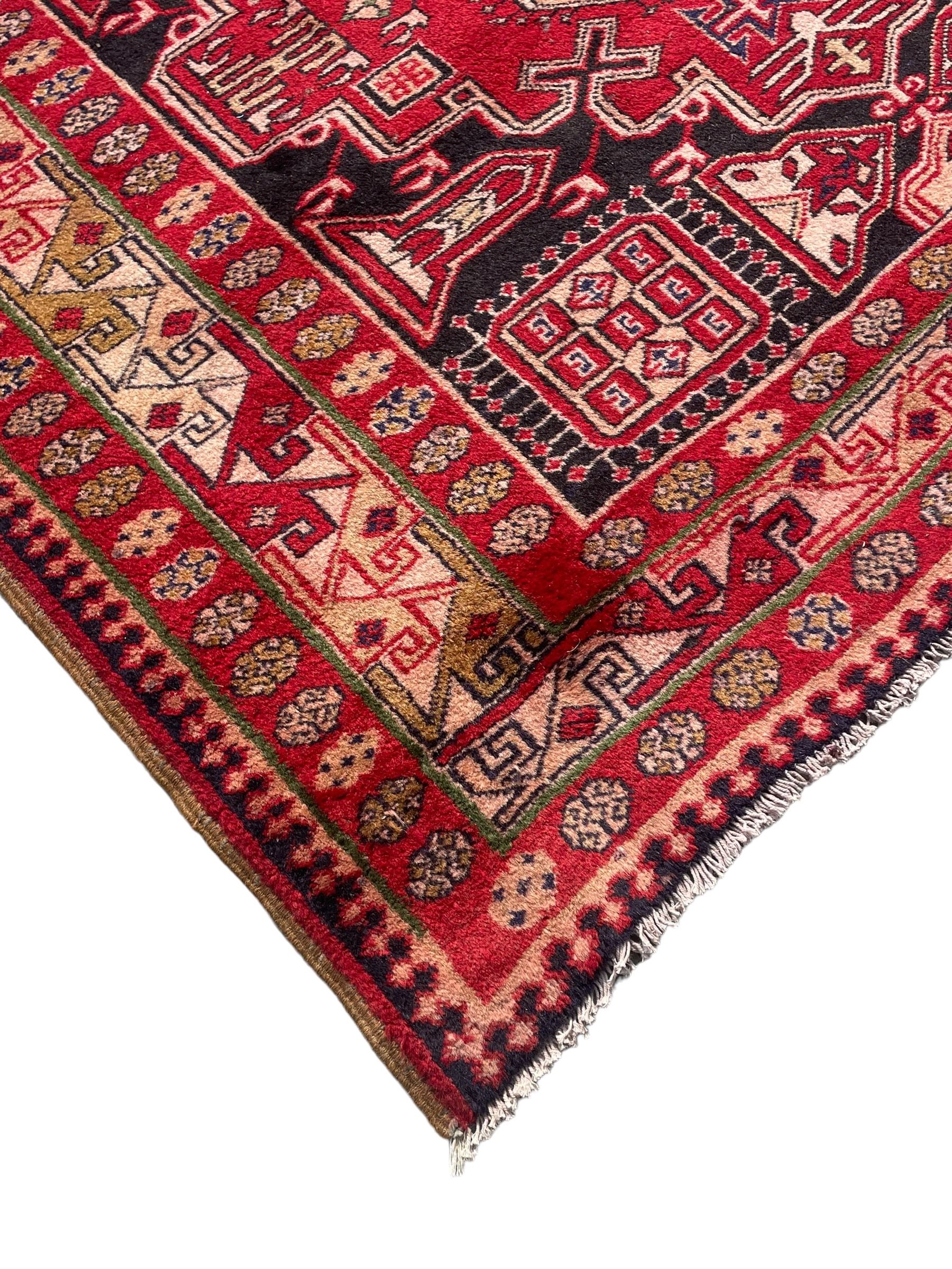 Persian Hamadan indigo and crimson ground rug, the field filled with three shaped medallions, overall geometric design, decorated with sandikli and hac motifs, geometric main border with repeating hooked motifs, within guard stripes decorated with small flower heads, outer crenelated fence band 