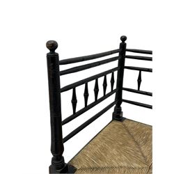 In the manner of William Morris - Arts & Crafts period corner chair, swell turned horizontal rails with balustrade back, rush seat on ring turned supports, black paint finish 