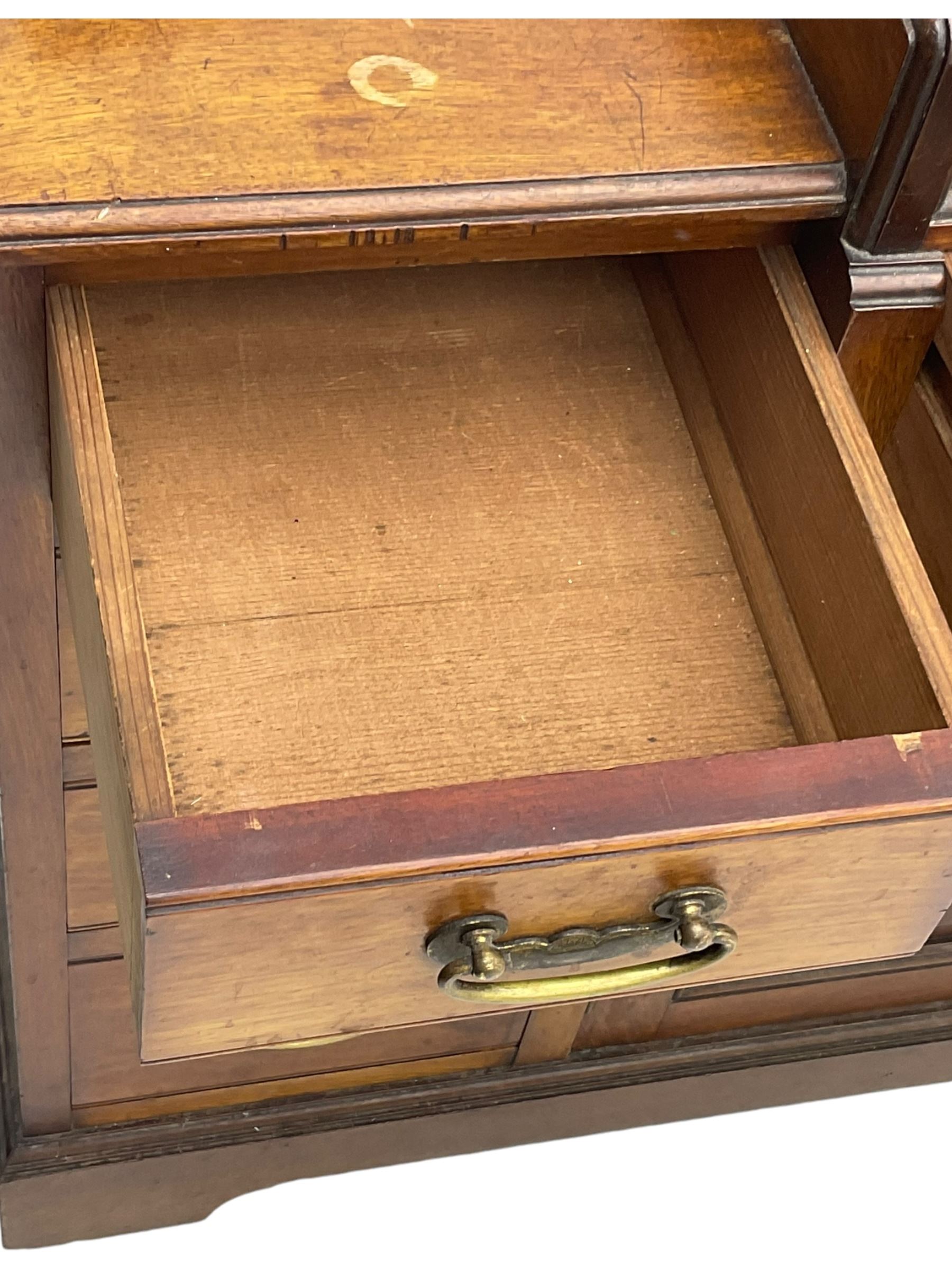 Victorian walnut clerk's desk, raised central section with tambour roll over hinged top, the interior fitted with leather inset writing surfaces, small drawers, document divisions and pen and ink stand, central drawer over double panelled cupboard, flanked by two banks of four graduating drawers, on bracket feet 