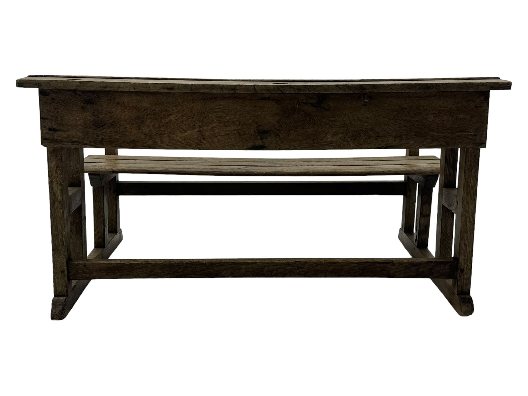 Victorian child's pine double school desk, the writing surface with two inkwells and two shelves underneath, integrated slatted bench seat raised on supports united by stretcher 