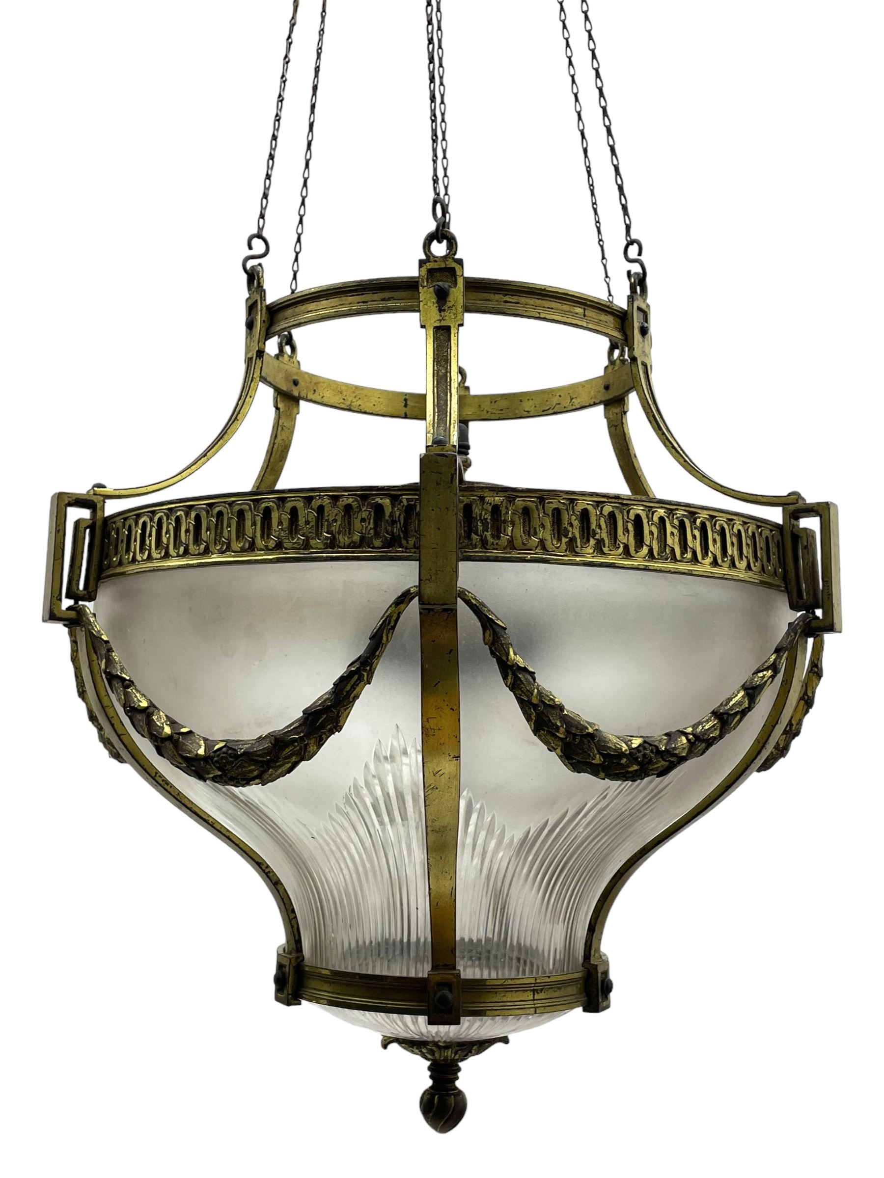 Edwardian brass ceiling light of circular bulbous form, moulded upper band over a guilloche cast central band united by shaped strapping, decorated with fruiting foliage festoons, fitted with frosted and vertical bevelled glass bowl, acanthus cast finial 