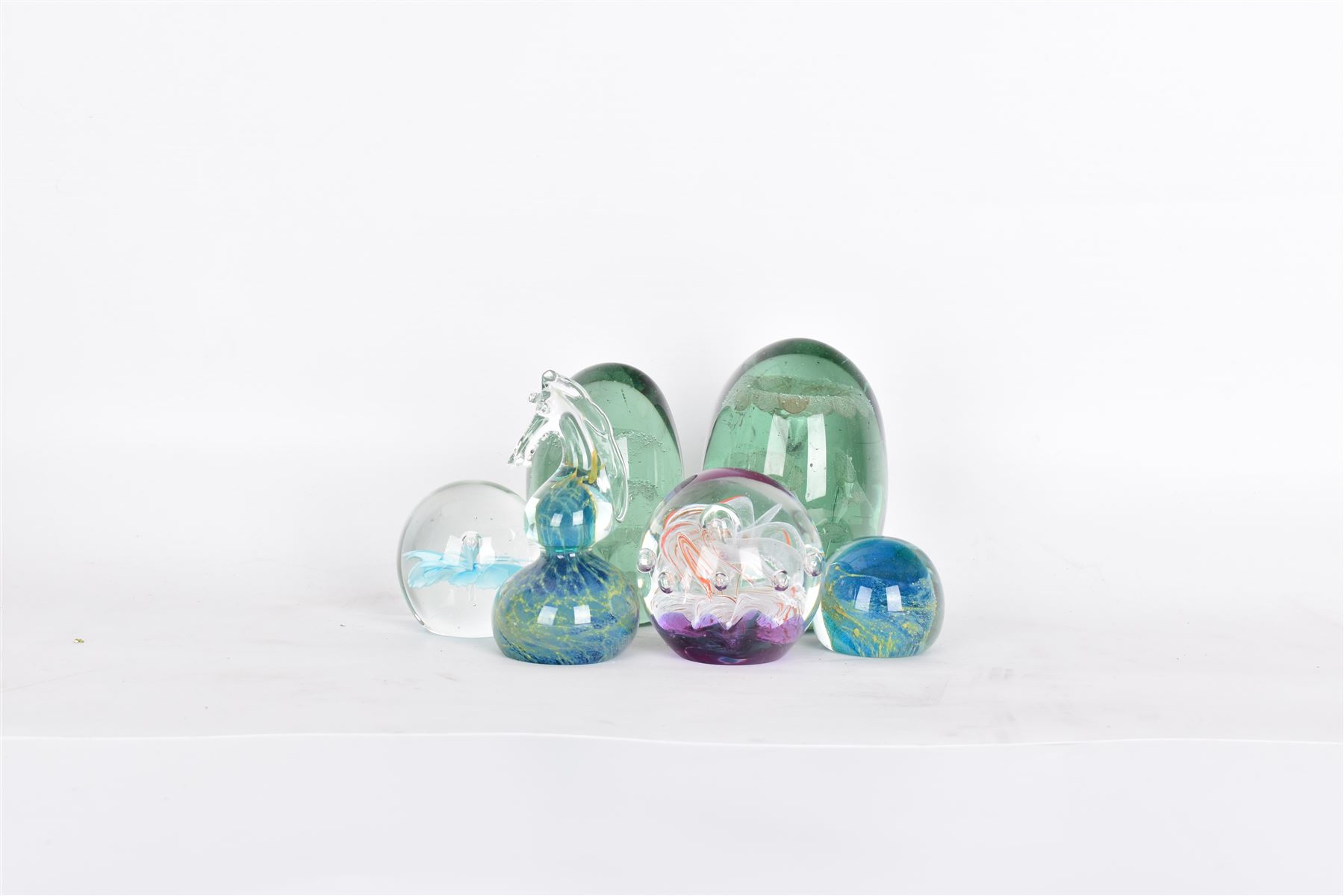 Two glass dump paperweights, with flower inclusions, together with four further glass paperweights