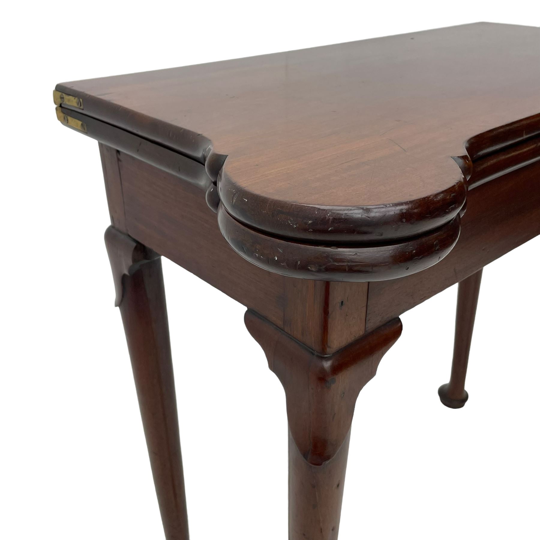 George III mahogany games table, the rectangular fold-over top with extending stepped rounded corners, opening to reveal baize lined interior with sunken counter wells, concertina action base, on lappet cabriole supports