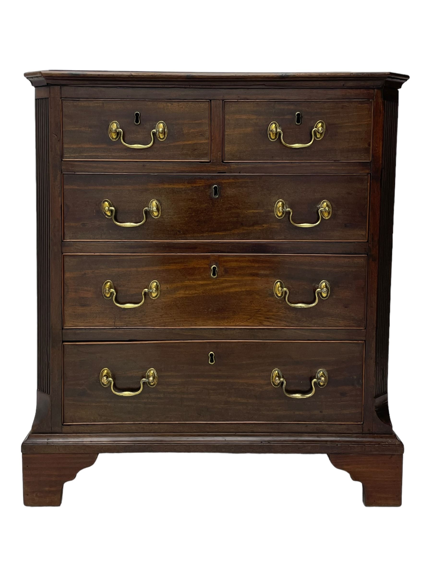 Small George III mahogany chest, rectangular canted form, moulded top over two short and three long cock-beaded drawers, fitted with brass swan neck handles and oval plates, enclosed by fluted upright corners, on bracket feet 