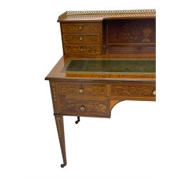 Edwardian inlaid mahogany writing desk, raised galleried back over inlaid central urn with scrolling leafy branches and six small drawers, satinwood banded rectangular moulded top with tooled leather inset, fitted with five drawers, the drawer facias inlaid with scrolling foliage and satinwood banding, square tapering supports inlaid with trailing bell flowers, on brass and ceramic castors 