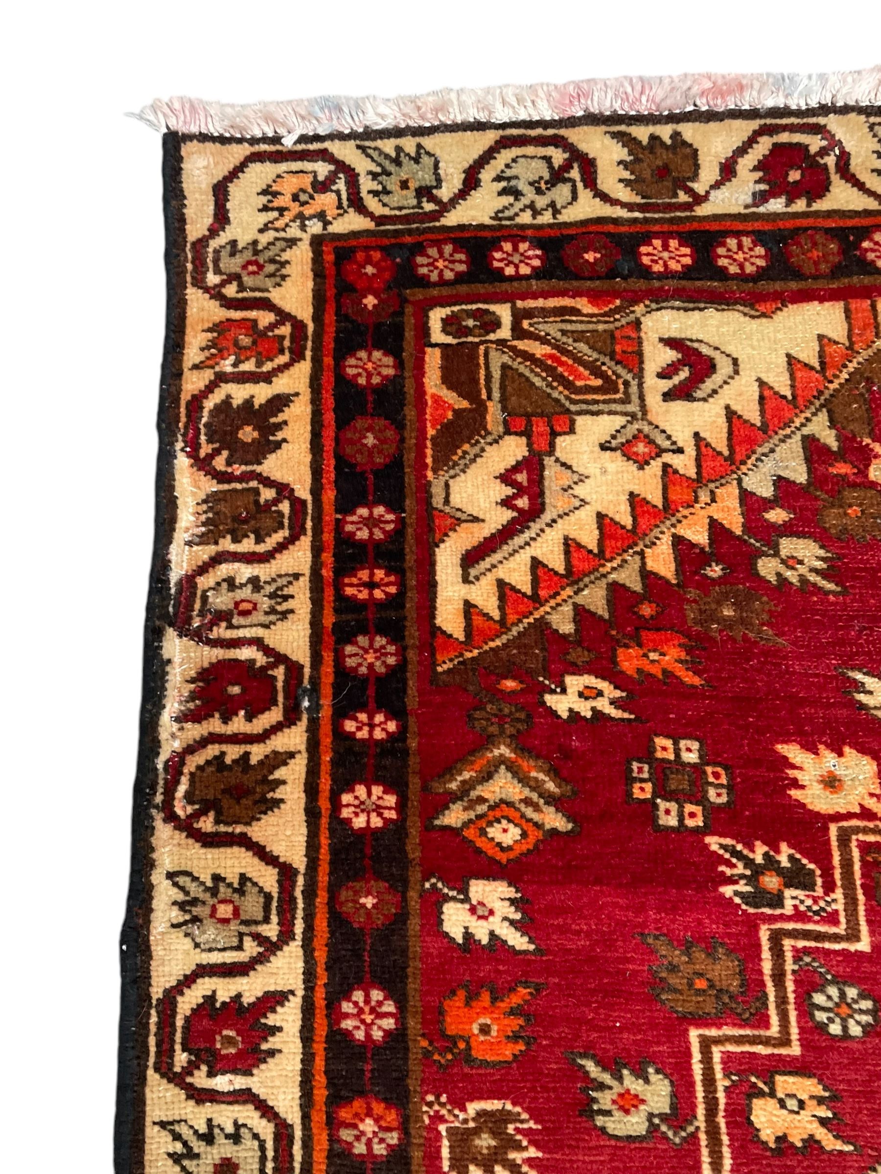 Persian crimson ground rug, the field decorated with three medallions within stepped borders, decorated all over with small stylised plant motifs, trailing flower head outer band and floral pattern border 