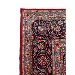 Persian Kashan crimson ground carpet, central rosette medallion on a field of trailing foliate branches decorated with palmettes, scrolling border with repeating plant motifs and flower heads, enclosed within floral pattern guard stripes