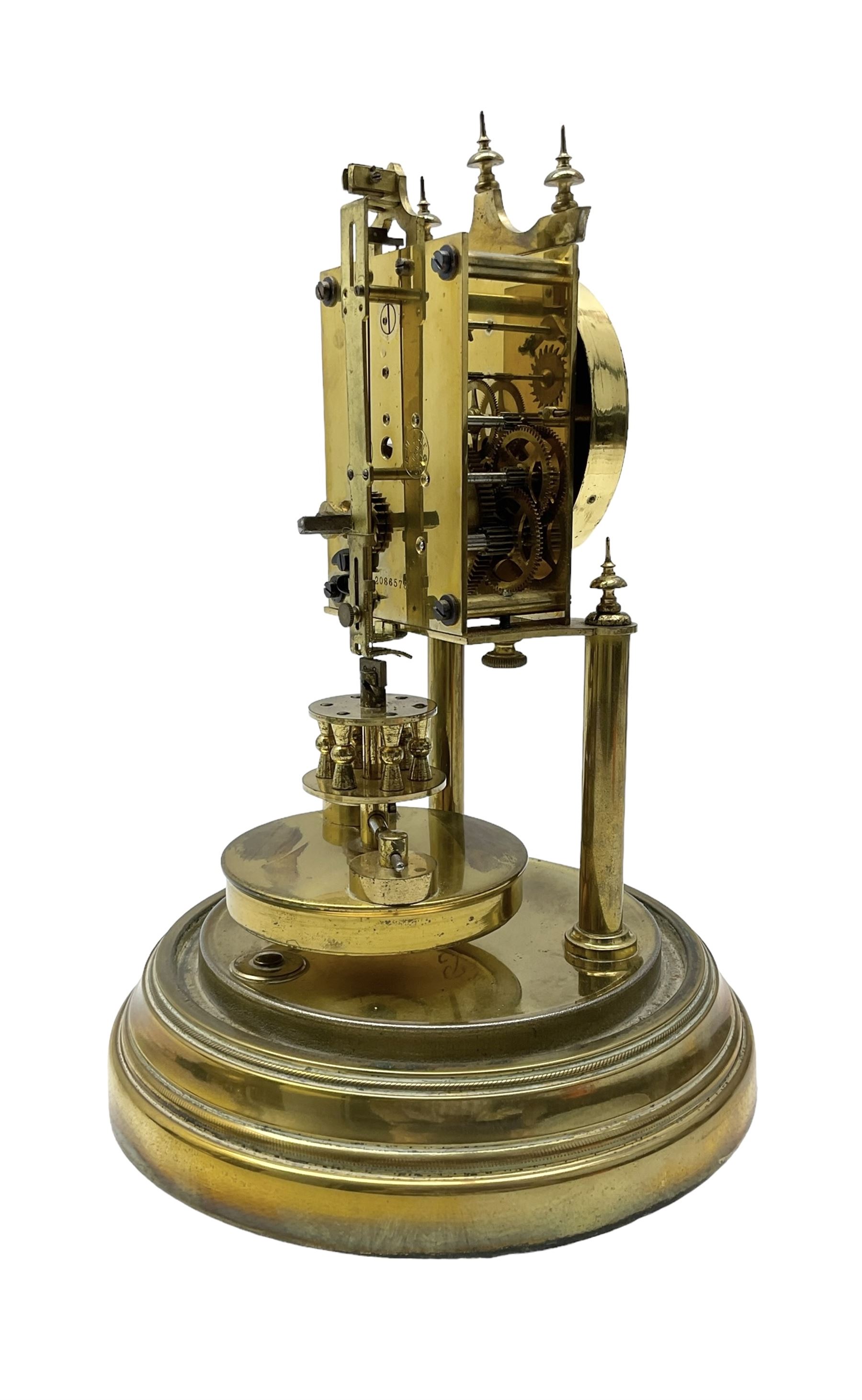 Gustav Becker - German torsion clock, serial No 2086578, on a circular brass base with a glass dome, silvered dial with Arabic numerals and steel spade hands, circular oscillating pendulum, torsion spring intact.