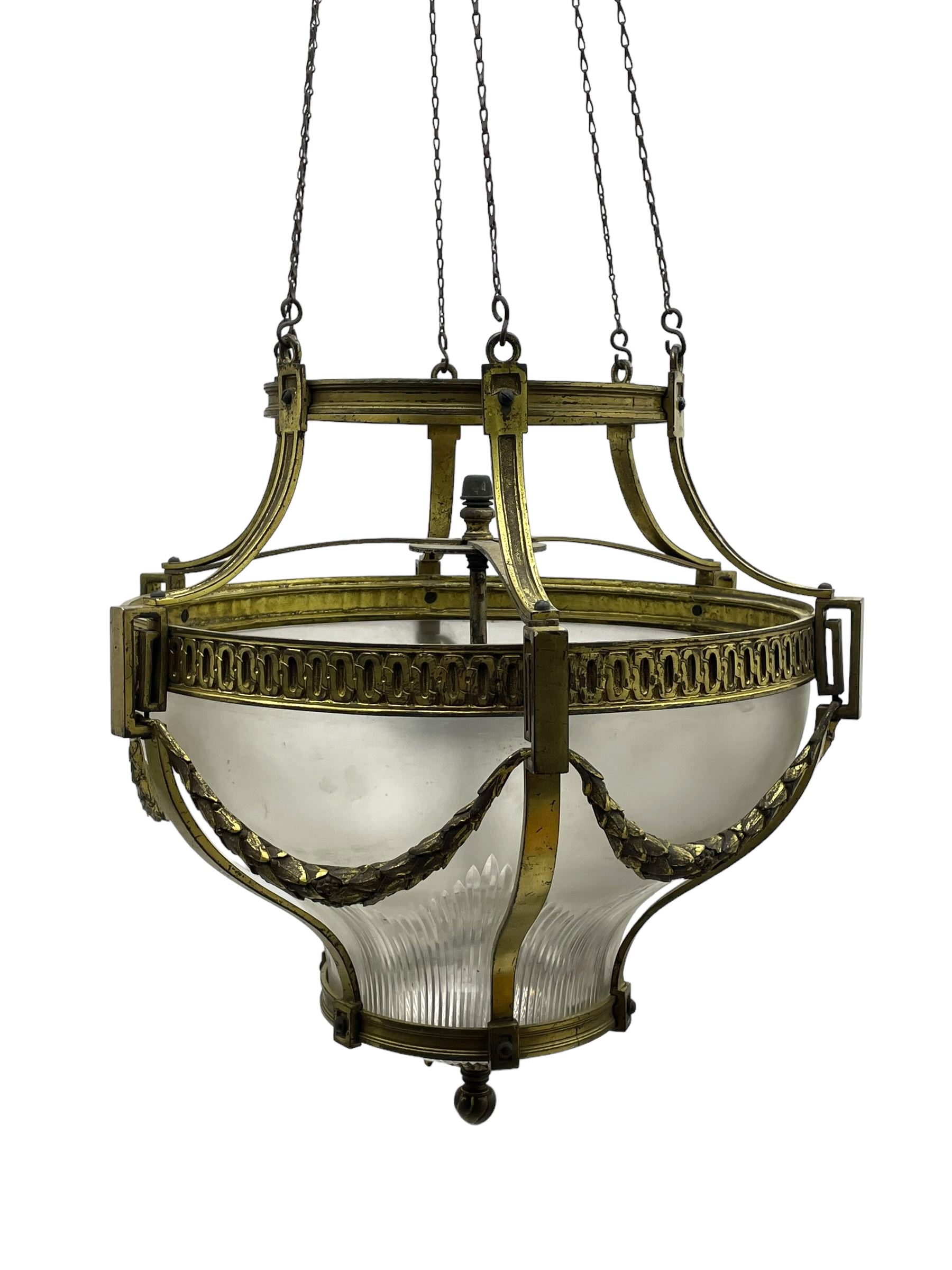 Edwardian brass ceiling light of circular bulbous form, moulded upper band over a guilloche cast central band united by shaped strapping, decorated with fruiting foliage festoons, fitted with frosted and vertical bevelled glass bowl, acanthus cast finial 