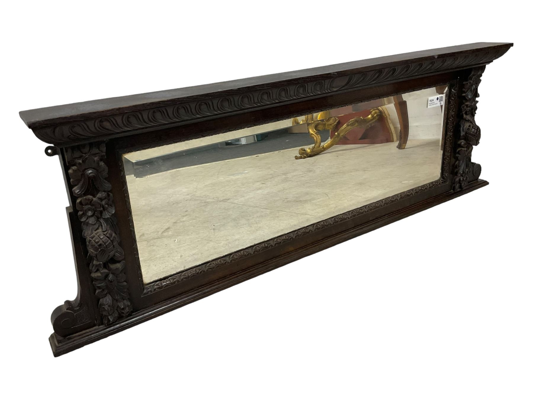 Victorian heavily carved oak wall mirror, projecting gadroon carved ovolo cornice, bevelled mirror plate within a lunette carved frame, decorated with applied fruit and foliage carved mounts, scroll carved brackets 