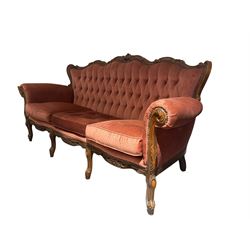 Late 20th century French walnut framed three-seat sofa, high shaped back with floral carved cresting rail, deep-buttoned coral velvet upholstery with loose seat cushions, scrolling arm terminals over moulded walnut frame, raised on cabriole supports