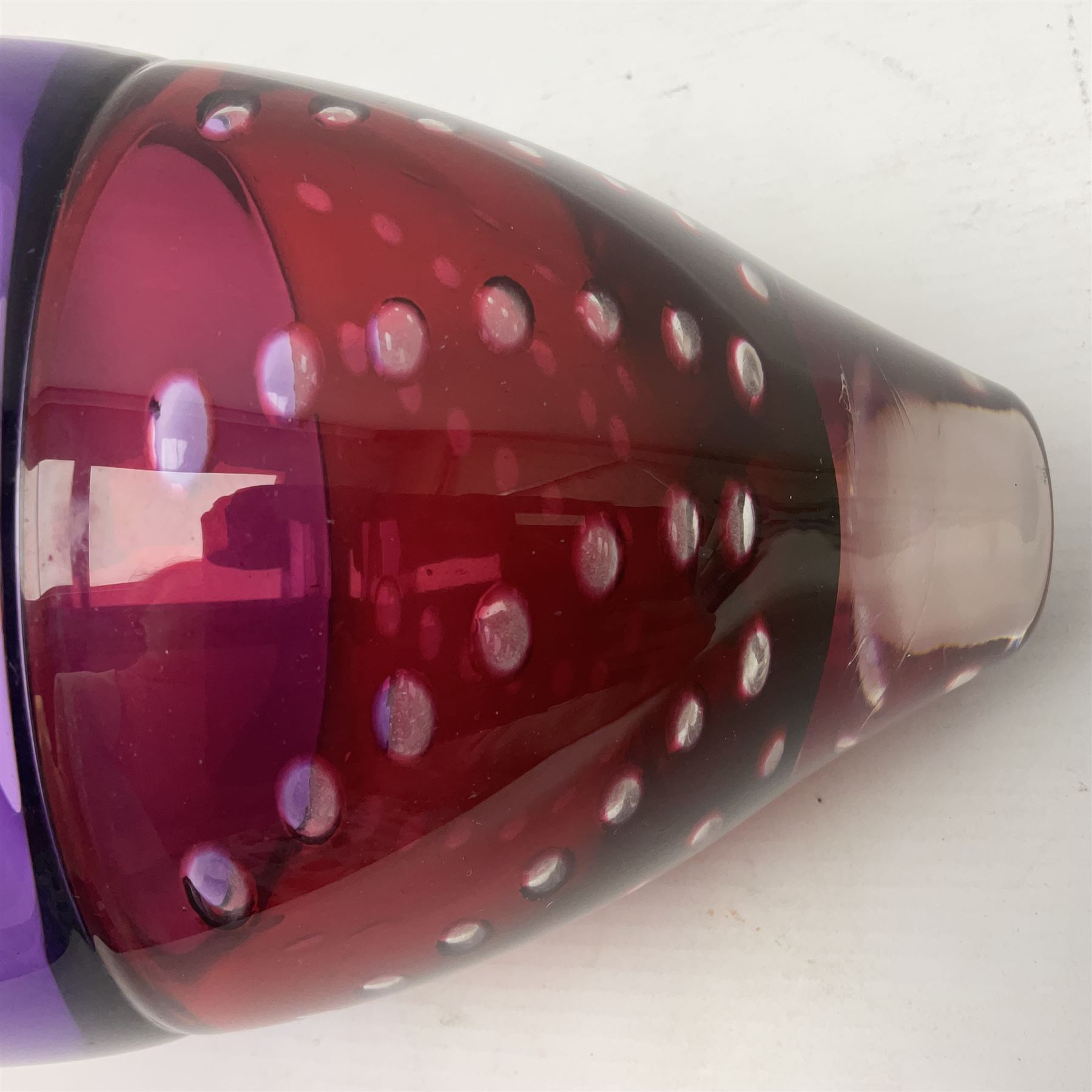 Stuart Akroyd tapering glass vase, purple banded top and cranberry red lower section with bubble inclusions, with sticker and engraved signature beneath, H19cm