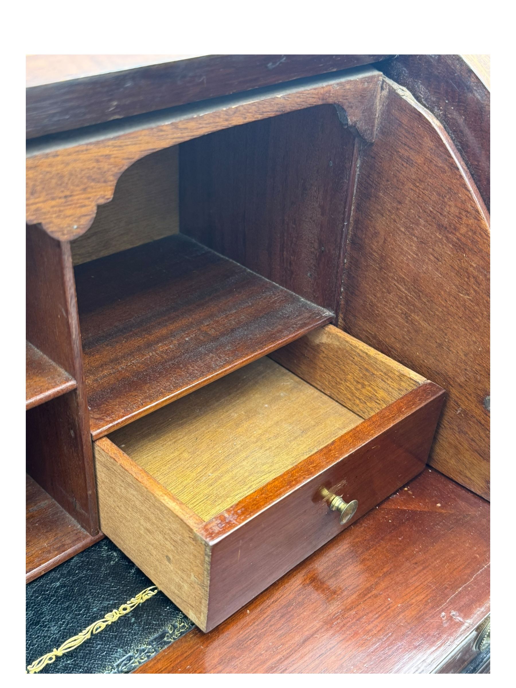 Edwardian inlaid mahogany roll-top desk, cylindrical lid enclosing fitted interior with pigeonholes, drawers and retractable writing surface, over two drawers with brass pull handles, on tapered supports with brass and ceramic castors