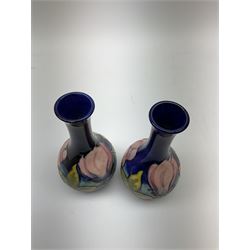 Pair of Moorcroft vases, decorated in the pink Magnolia pattern upon a dark blue ground, each with impressed mark beneath, H16cm.  