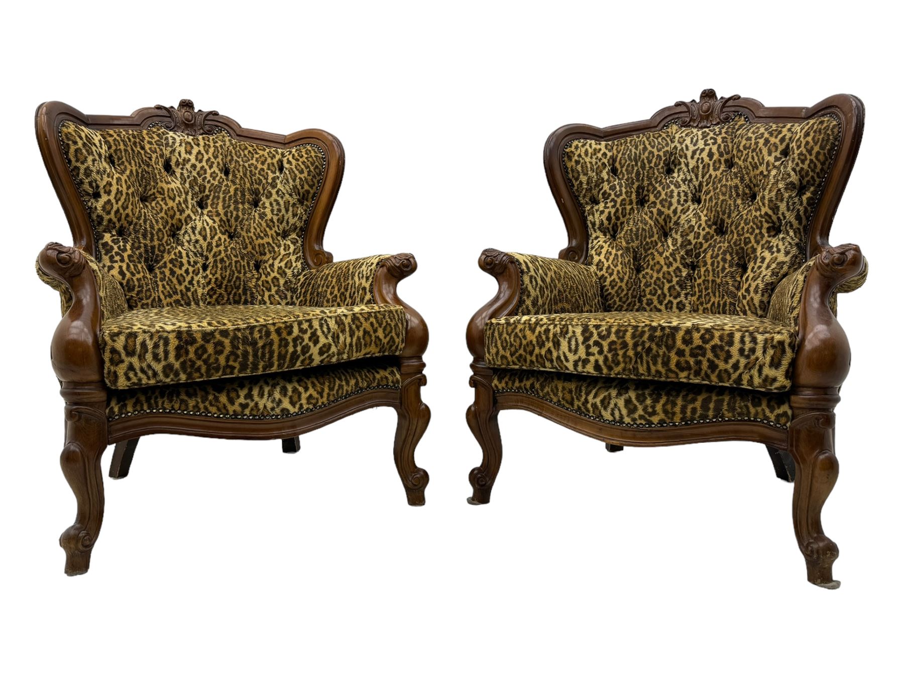 Pair of Victorian design stained beech armchairs, upholstered in leopard print fabric, with carved top rail over button-tufted backrest, scroll arms, serpentine front rail, raised on cariole supports