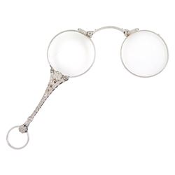 Early 20th century platinum and diamond lorgnette, the milgrain set rose cut diamond handle, with flower head terminals, the reverse with engraved foliate decoration, to spring-loaded glass lenses