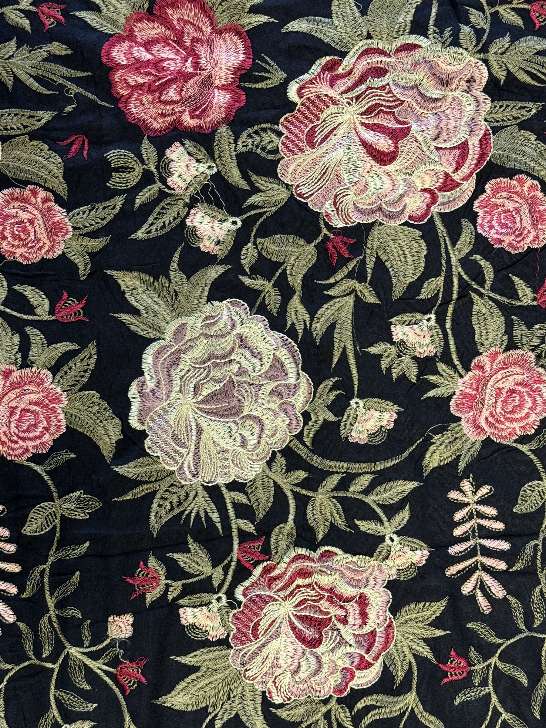 Embroidered Karandi fabric runner, the field featuring a black ground with an all-over floral design, including large pink and cream roses, accompanied by green leaves and small blossoms, bordered by plain sections at each end