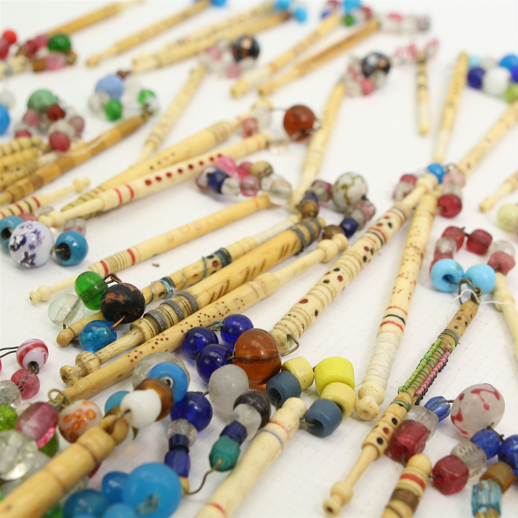 Collection of 19th century and later bone lace maker's bobbins, mostly engraved with names and spot incised blue and red decoration, others with brass wire work or turned shafts, most with glass spangles (60 approx)