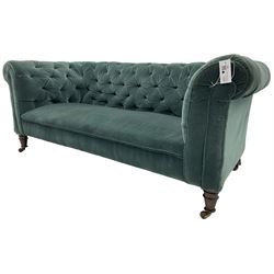 Victorian hardwood-framed Chesterfield sofa, traditional shape with low back and rolled arms, upholstered in teal buttoned fabric, on turned front feet with brass and ceramic castors 