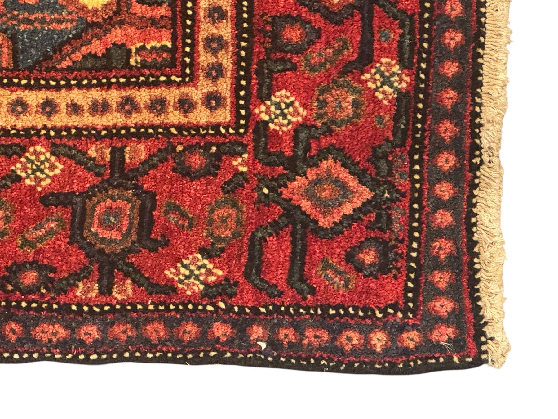 Northwest Persian Senneh crimson ground rug, central ivory lozenge medallion with geometric motifs, framed by matching spandrels, the surrounding field densely filled with stylised floral and foliate patterns, guarded border with repeating geometric and foliate motifs