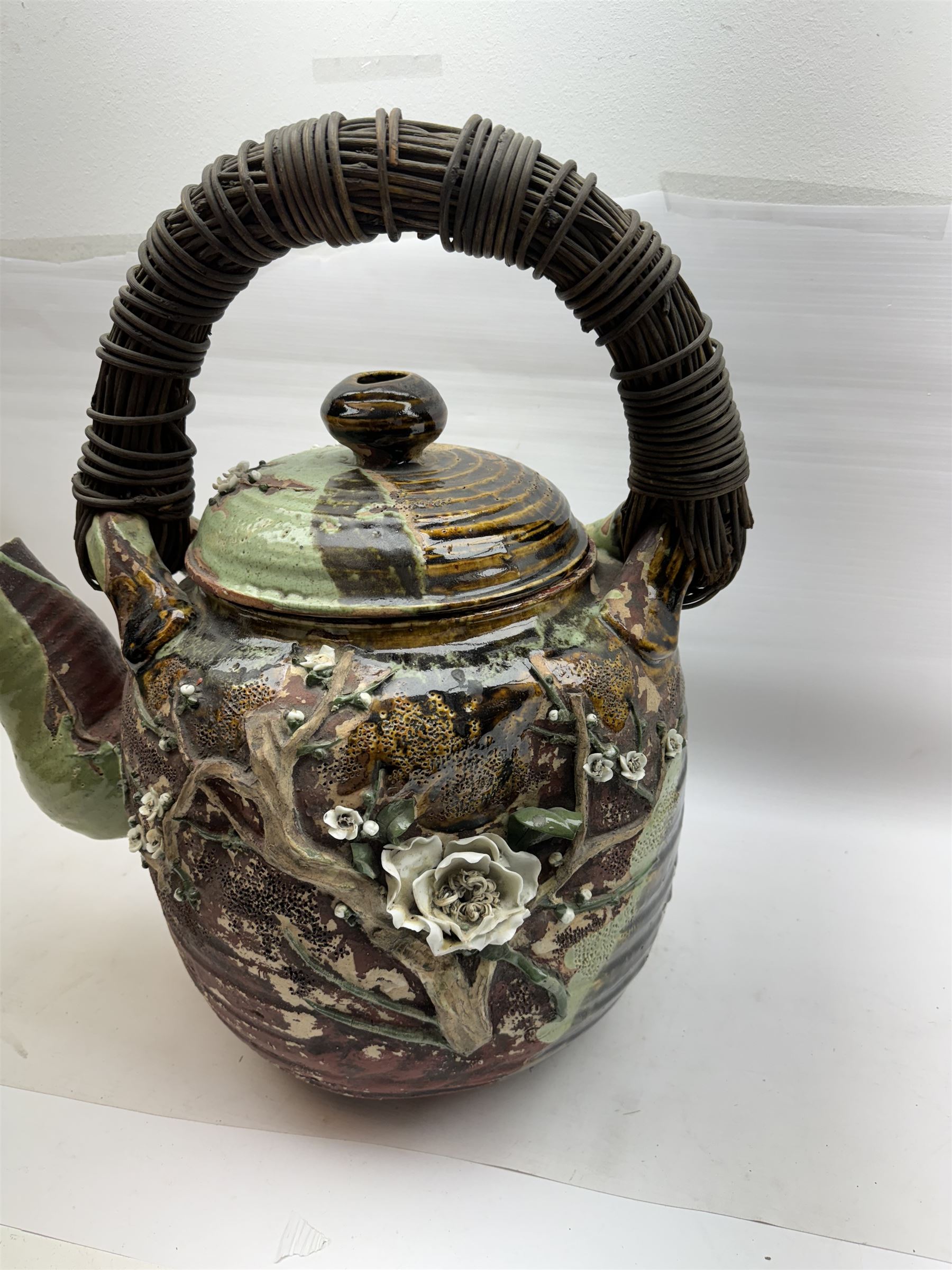 Very large Japanese Shigakari type coil built teapot, the body with a blossoming encrusted tree, woven loop handle and part green glazed spout and cover, H52cm