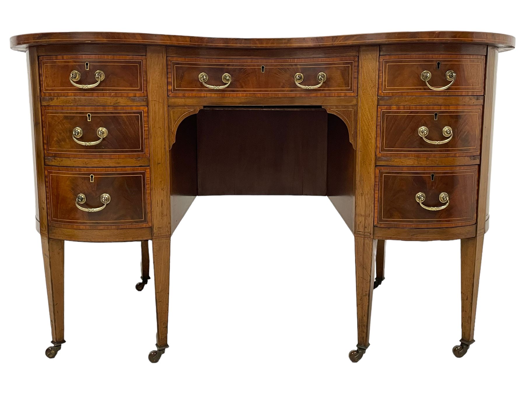 Edwardian mahogany and satinwood banded kidney-shaped writing desk, the shaped top with figured mahogany banding and boxwood stringing, fitted with seven drawers with satinwood bandings, on square tapering supports with brass and ceramic castors